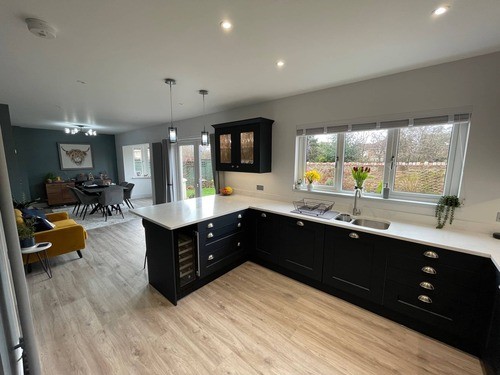 A blue and white Shaker kitchen with a wood floor and a yellow couch