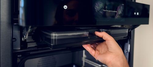 Hand opening black built-in kitchen appliance drawer