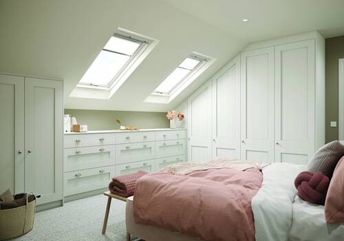 Attic bedroom with white fitted wardrobes and skylights