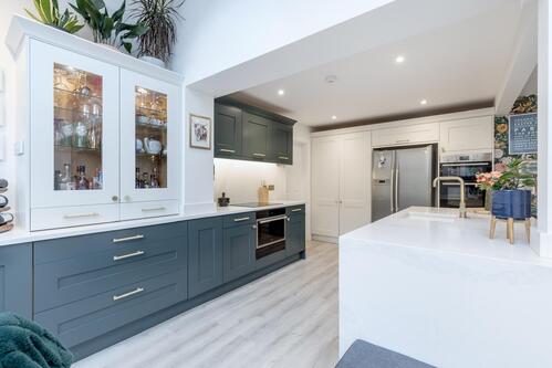 Two-tone blue and white kitchen with glass cabinet and island