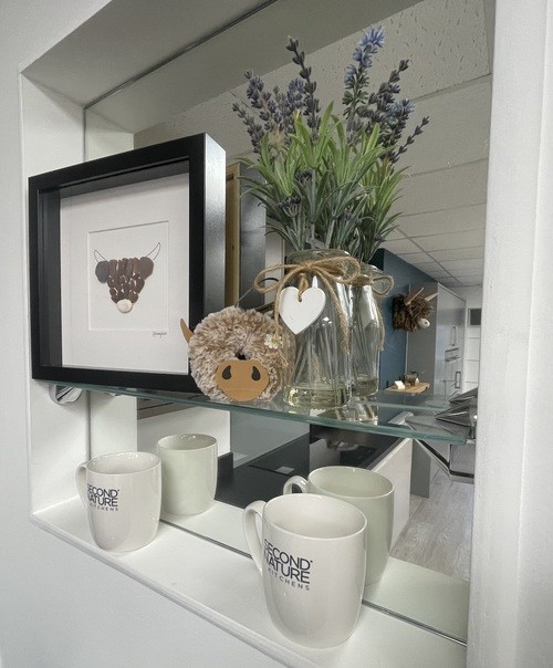 Kitchen shelf display with white mugs, lavender flowers, and framed artwork