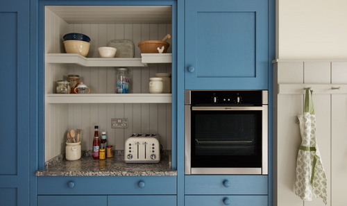Close-up of blue kitchen cabinet with built-in oven and open shelving