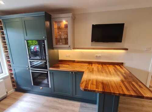 Teal kitchen cabinets with butcher block worktop and LED lighting
