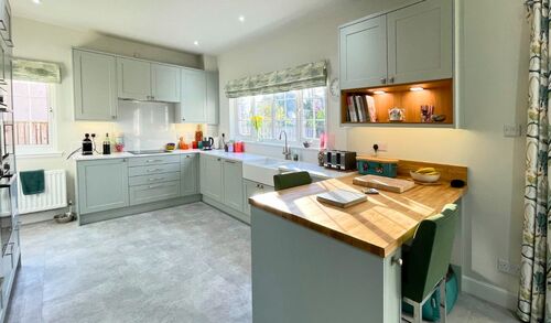 Modern grey kitchen with white countertops and large windows