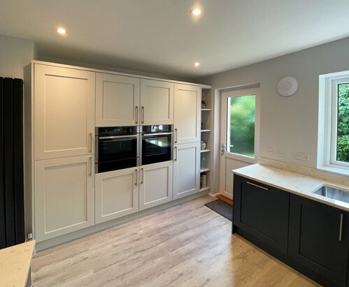 White kitchen cabinets with wooden countertops and grey tile backsplash