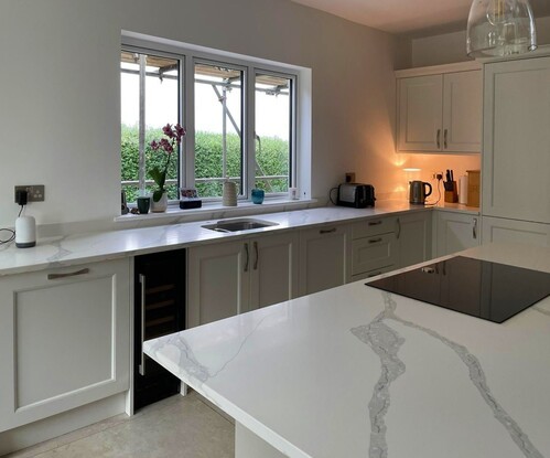 White kitchen cabinets with wooden countertops and grey tile backsplash