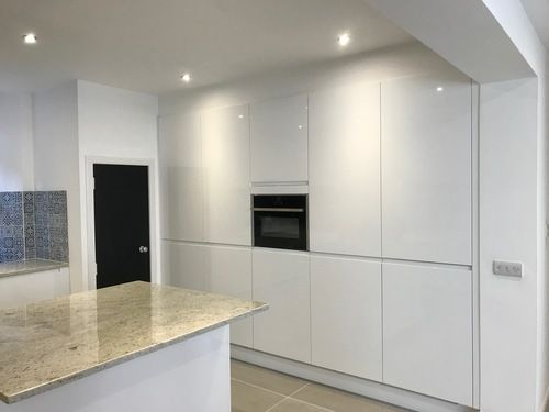 Modern white kitchen with granite worktop and built-in oven