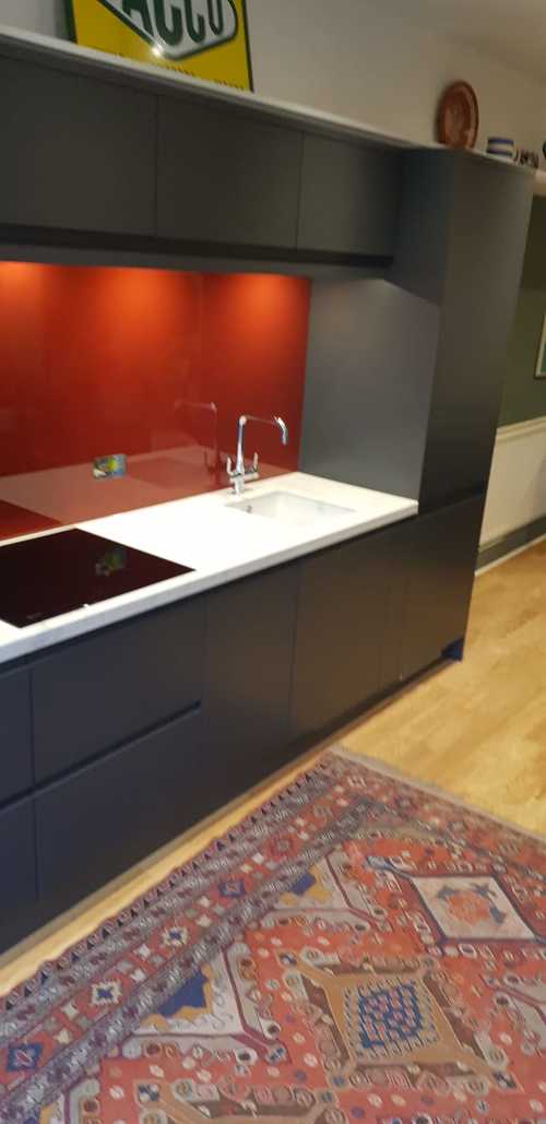 kitchen with black cabinets, red backsplash, and patterned rug