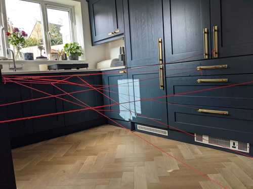 Navy kitchen cabinets with gold handles and red laser measurement lines