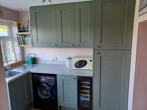 Utility room with sage green cabinets and integrated appliances