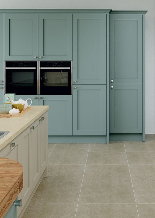 kitchen with sage green tall cabinets, double ovens and beige floor tiles