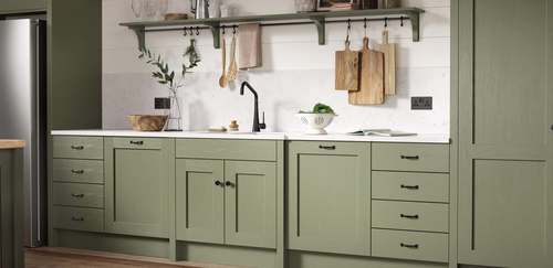 A classic green kitchen with pale splashback and green shelving.