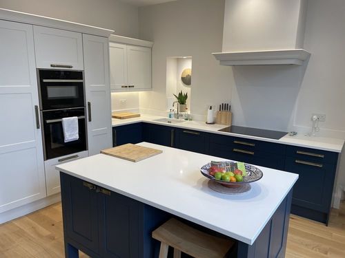 kitchen with navy and white cabinets, integrated appliances and white island