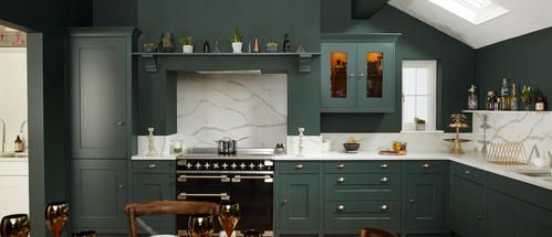 Dark green kitchen with marble backsplash, range cooker and wooden bar stools