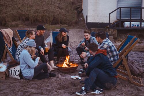 The Clean Life, image of people sitting around a fire pit on sand.