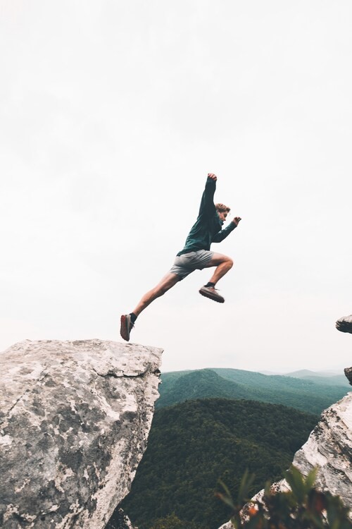 The Clean Life addiction recovery and trauma recovery resources, image of a man leaping off a rock with distant mountains behind him.