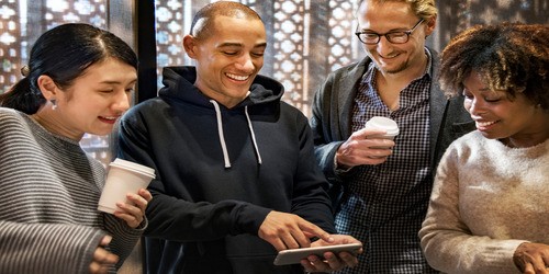 asian woman asian man caucasian man and black woman looking at a phone screen