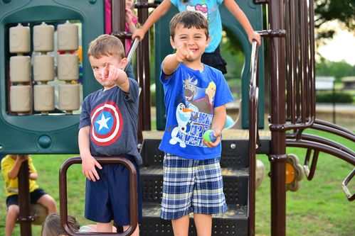 Young kids smiling and pointing on the playground