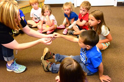 Kids church volunteer sharing hands on lesson with kids circled around
