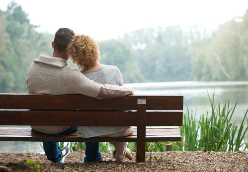 happy-couple-sitting-close-gazing-peacefully-at-lake