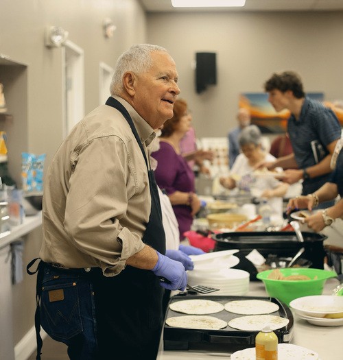 Old man serving lunch to crowd.