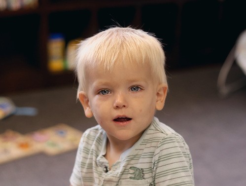 Blonde toddler boy smiling at the camera.