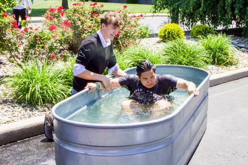 A Student baptizing another student near Cornerstone Christian Church's front entrance