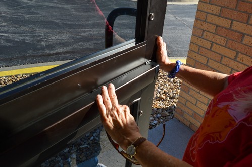 A woman in jeans and a t-shirt opens the door for people attending church on a Sunday morning