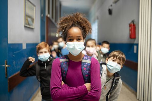 Group of school kids wearing face masks in classroom during corona virus.