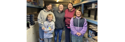 Laura and her children hwlp a staff member organize dry storage.