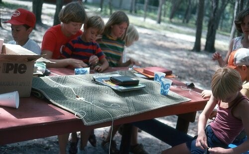 Youth sitting at old picnic tables.