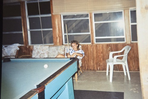 Person sitting in front of a pool table.