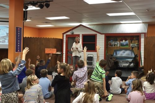 Classroom with brown fence and a teacher in a white sweater interacting with children