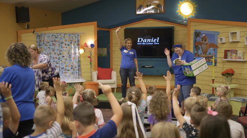 Colorful classroom with teachers in blue shirts interacting with children