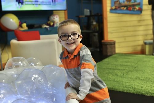 Little boy with orange and gray shirt playing with clear inflatable balls