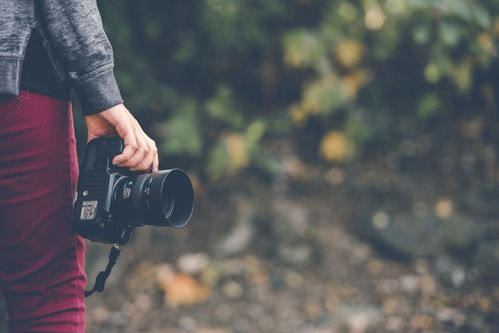 a woman in a forest holding a camera