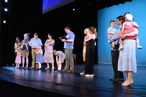 Families participating in a child dedication ceremony on stage at Restoration City Church.