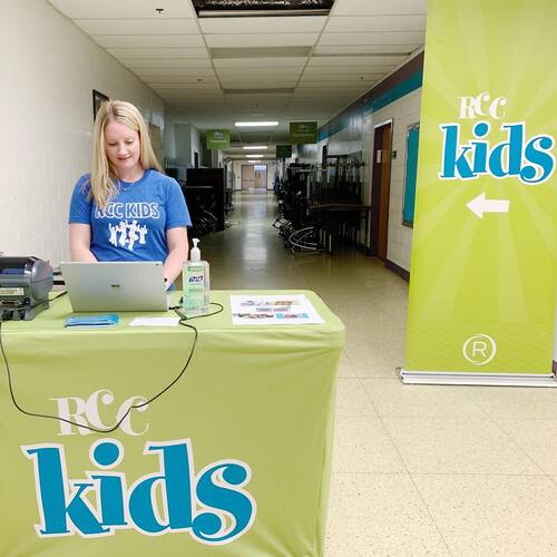 RCC Kids check-in station staffed by a volunteer welcoming families to the children’s ministry at Restoration City Church.