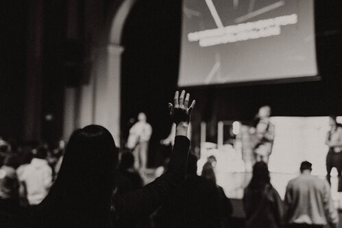 a woman raising her hand in worship