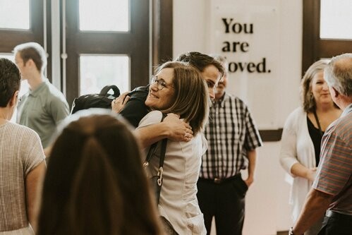 A middle aged woman hugging a young man and smiling