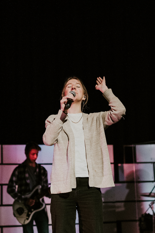 a woman leading worship with her eyes closed and hand raised
