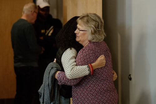 an elderly woman hugging a younger woman of color