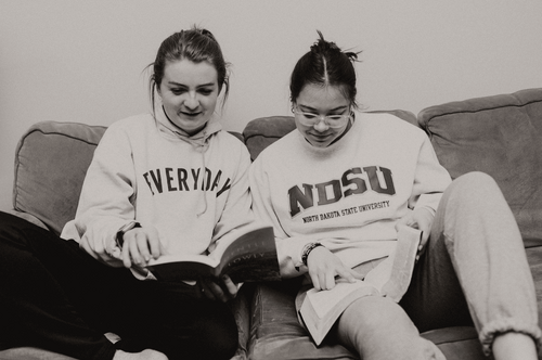 two women reading on a couch