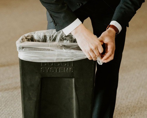 someone tying a garbage bag around the trash bin