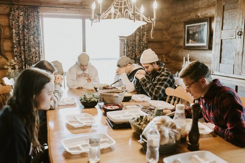 two greeters waving and holding church doors open