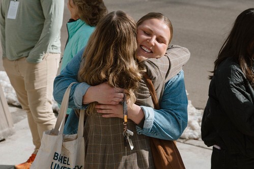 A group of people sitting together and smiling, a young asian woman in the center is laughing
