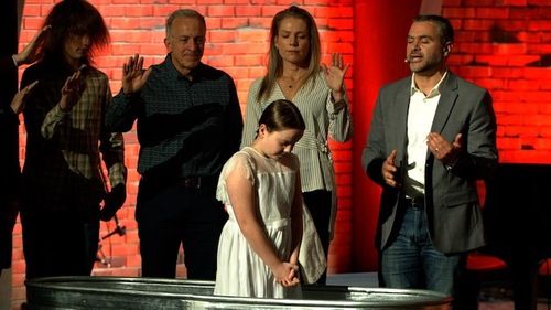 Elementary aged girl being baptized in a tank in the worship center