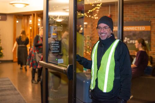 Volunteer holding the door open to the community room