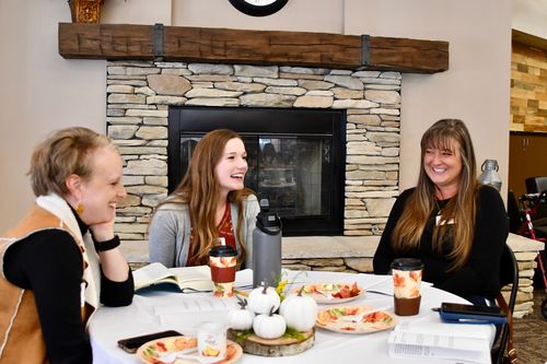 Three women talking at a table at a women's conference