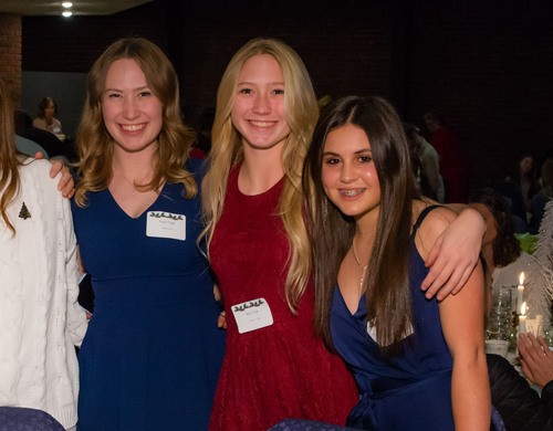 Three teenage girls with their arms over each other's shoulders